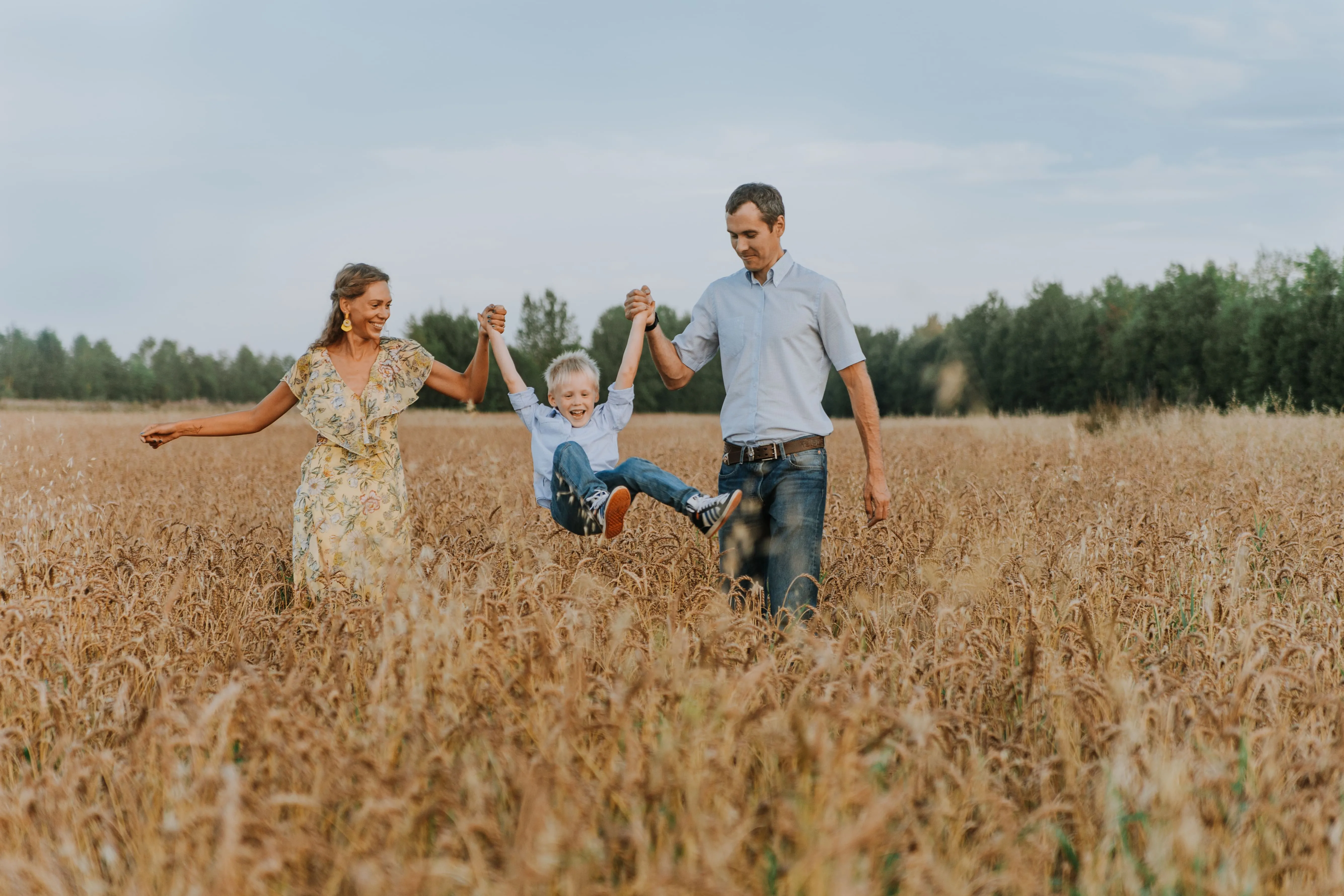 Family walking through a wheat field, laughing