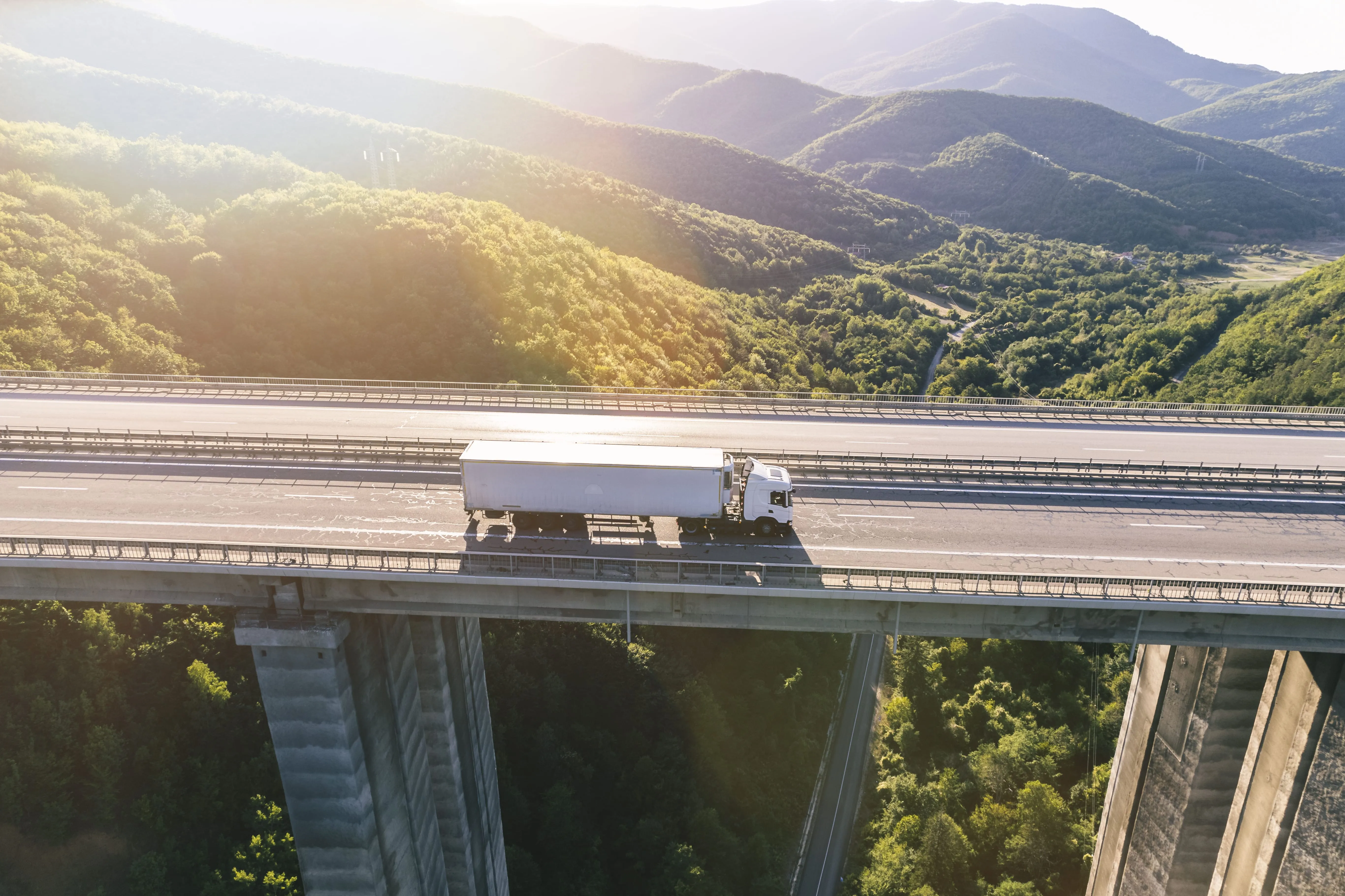 Trucks on a highway in front of mountains at sunset